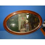 An oval Mahogany framed bevelled wall mirror, 19 1/2" x 31".