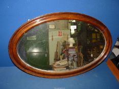 An oval Mahogany framed bevelled wall mirror, 19 1/2" x 31".