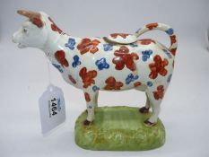 A 19th century, circa 1830 Welsh pottery cow creamer with red and blue patches,
