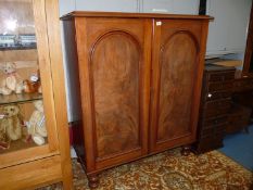 A circa 1900 Mahogany cupboard having a pair of opposing recessed arched panelled doors and