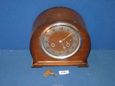 A Mantle clock, 9'' wide x 8 1/4'' high, with key and pendulum.