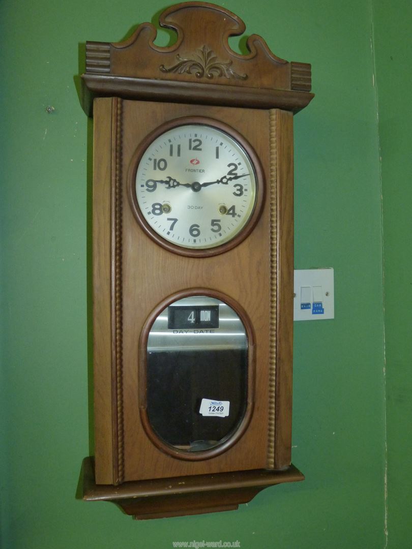 A Frontier 30 day chiming Clock in medium toned wooden case having day and date perpetual calendar