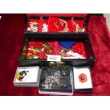 A black jewellery box containing costume jewellery, brooches, hair grips etc.