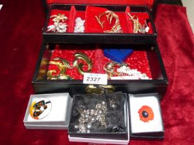 A black jewellery box containing costume jewellery, brooches, hair grips etc.