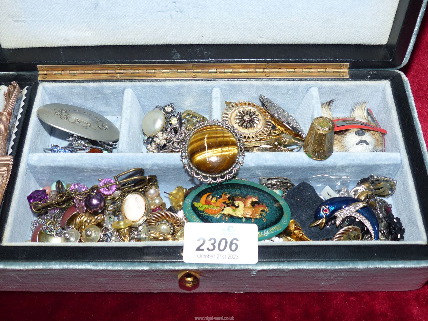 A jewellery box containing brooches, clip on earrings and pierced earrings.