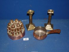 A copper jelly mould and small pan and a pair of candlesticks.