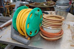 A quantity of terracotta saucers and a hose on reel.