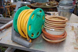 A quantity of terracotta saucers and a hose on reel.