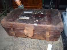 A brown leather suitcase marked 'Junior Army & Navy Ltd' with remnants of railway labels,