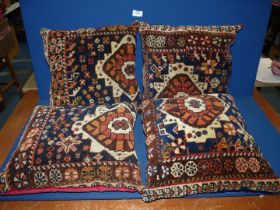 A set of four carpet cushions with velvet backs (two blue and two red).