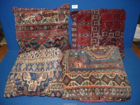 Four old carpet cushions in red and blue geometric pattern and red backs.