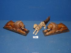 A pair of carved figures of reclining lions and an unusual cat type figure covered in fur.