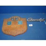 A wooden shield shaped plaque mounted with Chevrolet badges including 1976 Chevrolet Monza Coupe