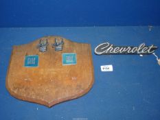 A wooden shield shaped plaque mounted with Chevrolet badges including 1976 Chevrolet Monza Coupe
