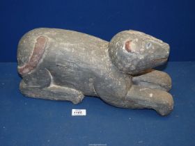 A heavy carved wooden figure of a stylized feline with painted details to the eyes, ears and tail,