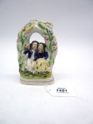 A small Staffordshire flatback of a courting couple under a flower arch,