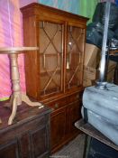 A contemporary Yew wood finished bookcase over cupboard,