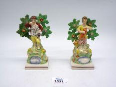 A pair of early Staffordshire Bocage figures; a boy and girl with dogs in front of foliage.