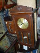 A Wall Clock in darkwood case and glass panelled door,
