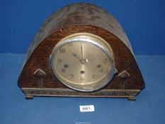 A dark wood domed Mantle clock with two diamond shapes to front and in a floral design to rim with