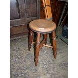 A rustic circular Elm seated stool raised on four turned Ash wood legs with a cross stretcher,