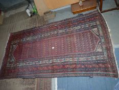 A bordered, patterned and fringed Rug in red, blue and cream, 78'' x 39''.