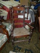 An antique high ladder back open armed Armchair having a distressed rush seat,