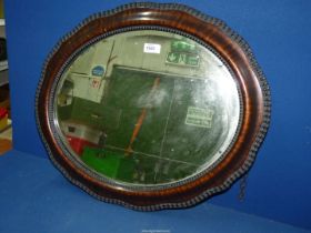 An Edwardian oval bevelled mirror, 25" x 21".