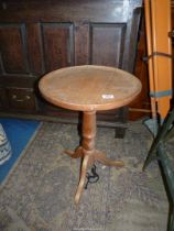 A light Oak circular pedestal table having a turned pillar and three splay feet,