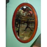 A large late 19th century oval bevelled mirror with Mahogany frame beaded decoration, 28" x 18".