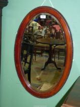 A large late 19th century oval bevelled mirror with Mahogany frame beaded decoration, 28" x 18".