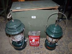 Two vintage Coleman camping lanterns in green wooden crate.