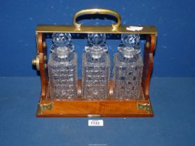 A Betjemann's wood and brass Tantalas with three cut glass decanters, makers Lloyd Payne Amie,