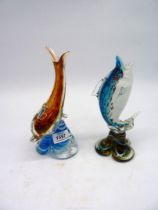 Two glass animals, dolphin and fish.