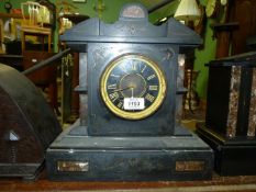 A slate and marble mantle clock with Roman numerals to the face and engraved detail to the front,