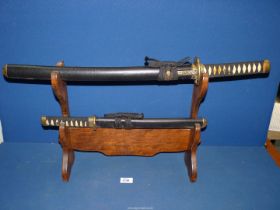 A hardwood sword stand with two replica Japanese swords.