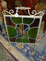 An early 20th century scroll frame, brass fireguard enclosing a stained glass panel, 38" x 18".