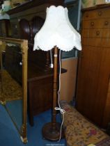 A darkwood standard lamp having an octagonal cream shade with tasselled details.