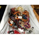 A wicker tray of costume jewellery incluidng bead necklaces, etc.