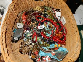 A large wicker basket of costume jewellery, bead necklaces, etc.