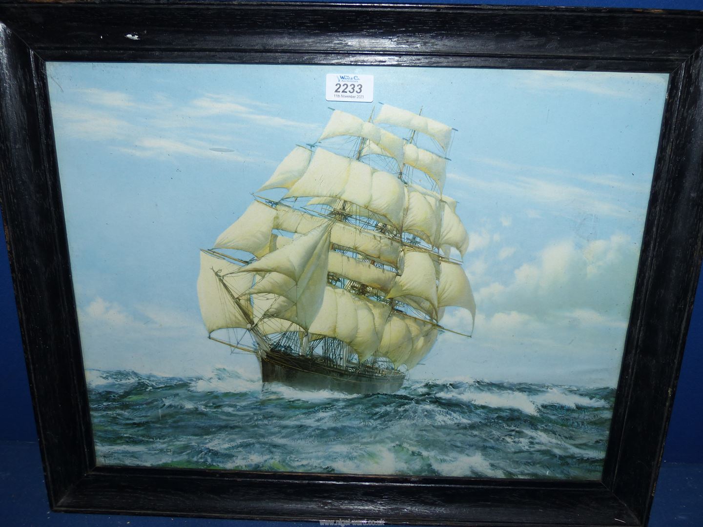 A framed and glazed print of a tall ship in full sail on a choppy sea, no visible signature.