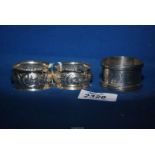 A pair of silver napkin rings, Chester (hallmarks rubbed) and a silver napkin ring, Birmingham 1880,