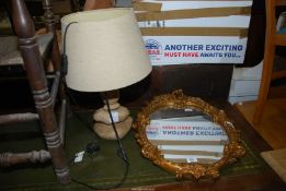 A table lamp and framed oval mirror.