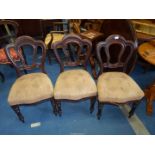 Three dining chairs with upholstered seats.