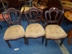 Three dining chairs with upholstered seats.