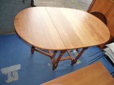 An oval drop leaf gateleg dining table, 59 1/2'' when open x 36'' x 29'' high, 21 1/2'' when closed.