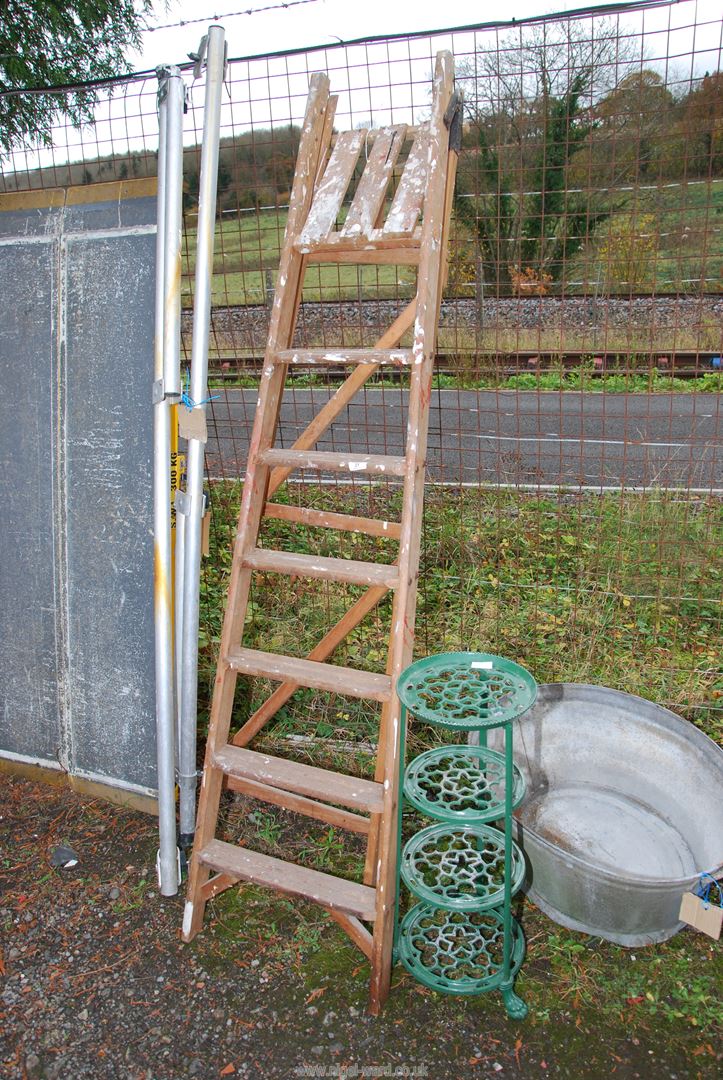 A seven rung wooden stepladder and a green cast pot stand.