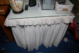 A glass top dressing table having broderie anglaise valance.