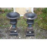Two cast iron urns on cast iron bases, 20'' high and 8'' square bases.