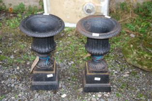 Two cast iron urns on cast iron bases, 20'' high and 8'' square bases.